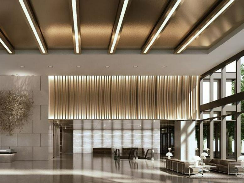 Spacious reception lobby with warm linear ceiling lights and a decorative wood-slat feature wall.