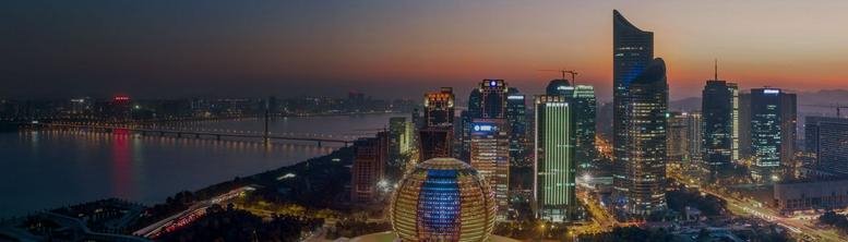 Panoramic view of the illuminated city skyline and river at dusk.