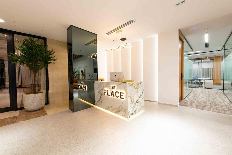 Modern marble reception desk at the King Fahd Road building with a branded wall and warm accent lighting.