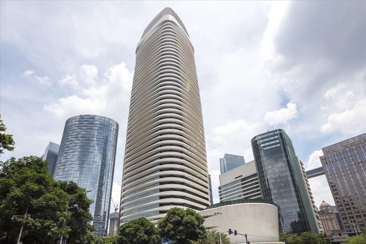 Exterior view of the tall, curved Kingold Century Centre skyscraper against a bright sky.