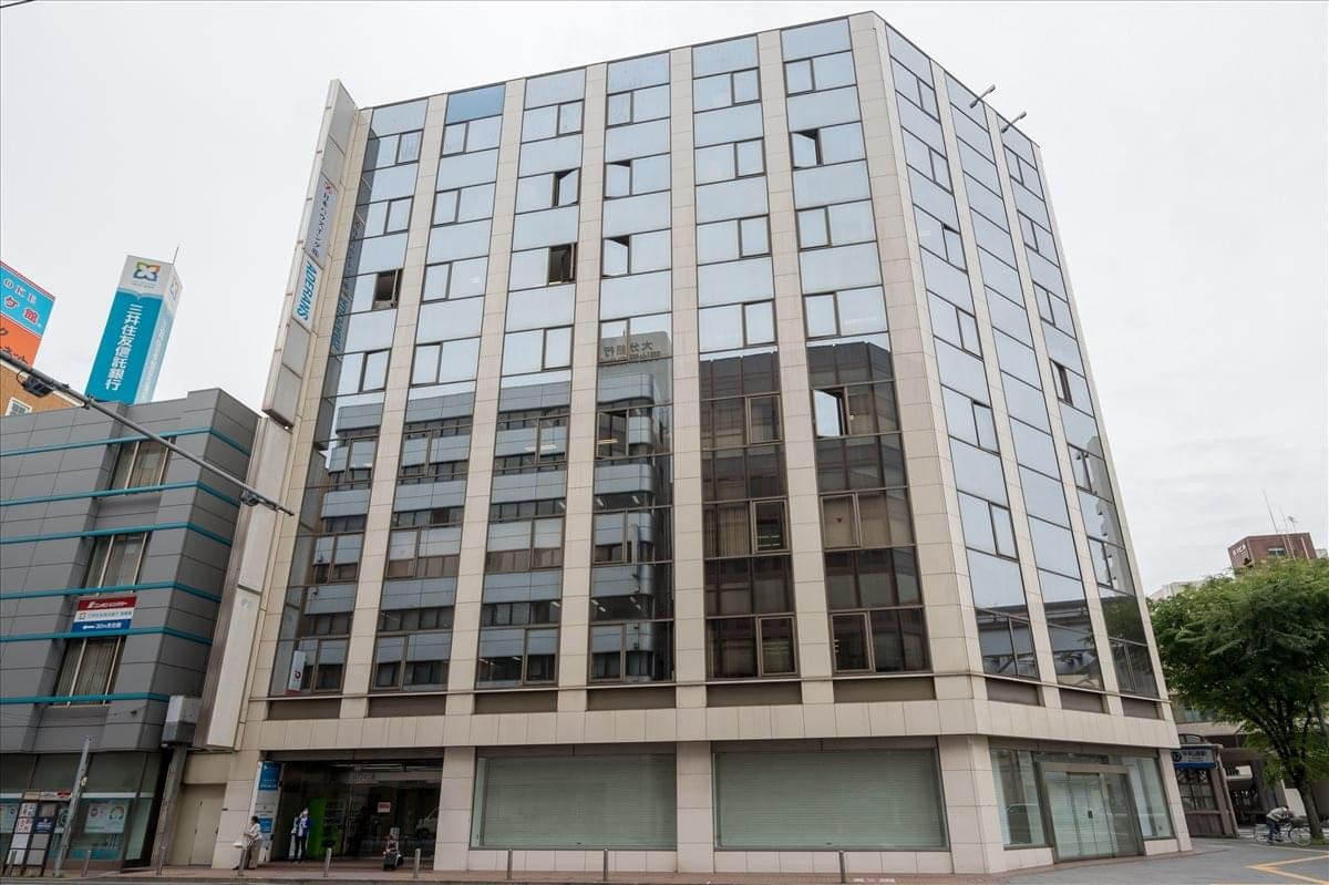 Exterior view of the Kitakyushu Toyo Building 3F & 5F featuring a grid facade of glass and stone.