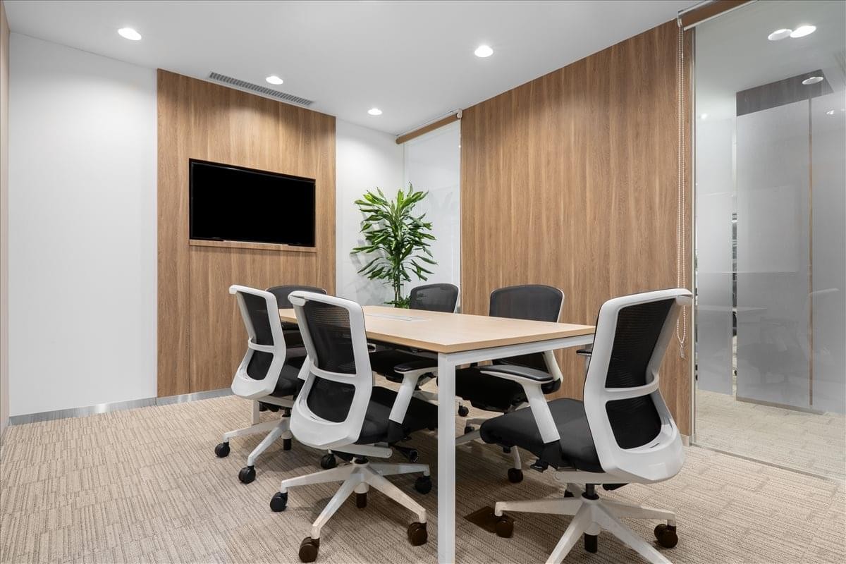Modern meeting room with wood-paneled walls, a wall-mounted TV, and white chairs.