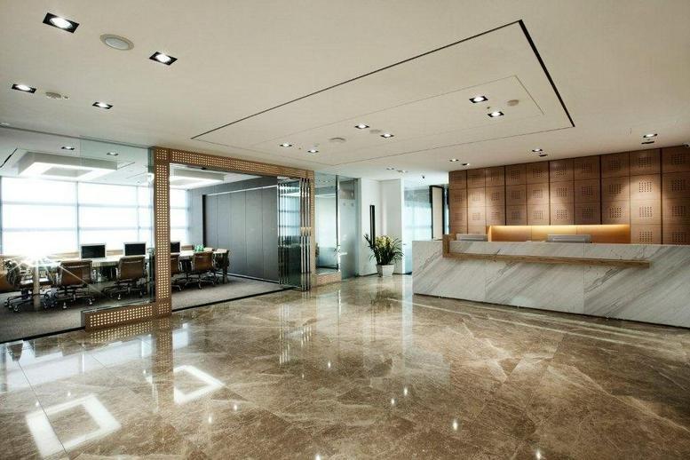 Elegant reception lobby with polished marble floors and a curved stone front desk.