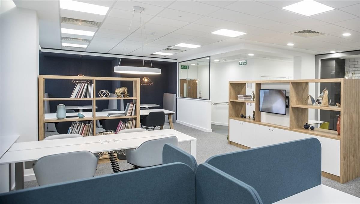 Spacious open-plan workspace at The Enterprise with modern desks and bookshelves.