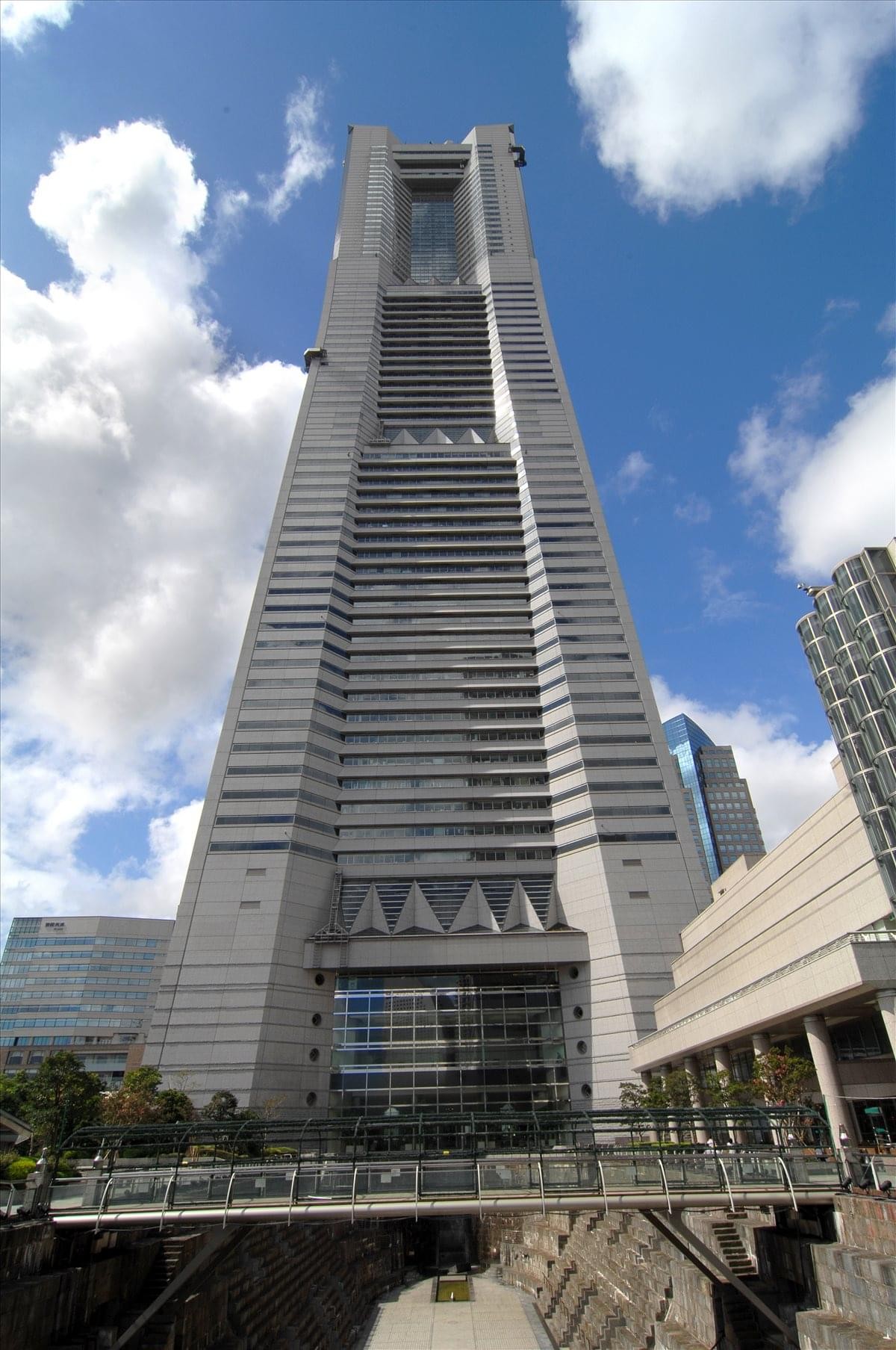 Low-angle exterior view of the soaring glass and steel Yokohama Landmark Tower against a blue sky.