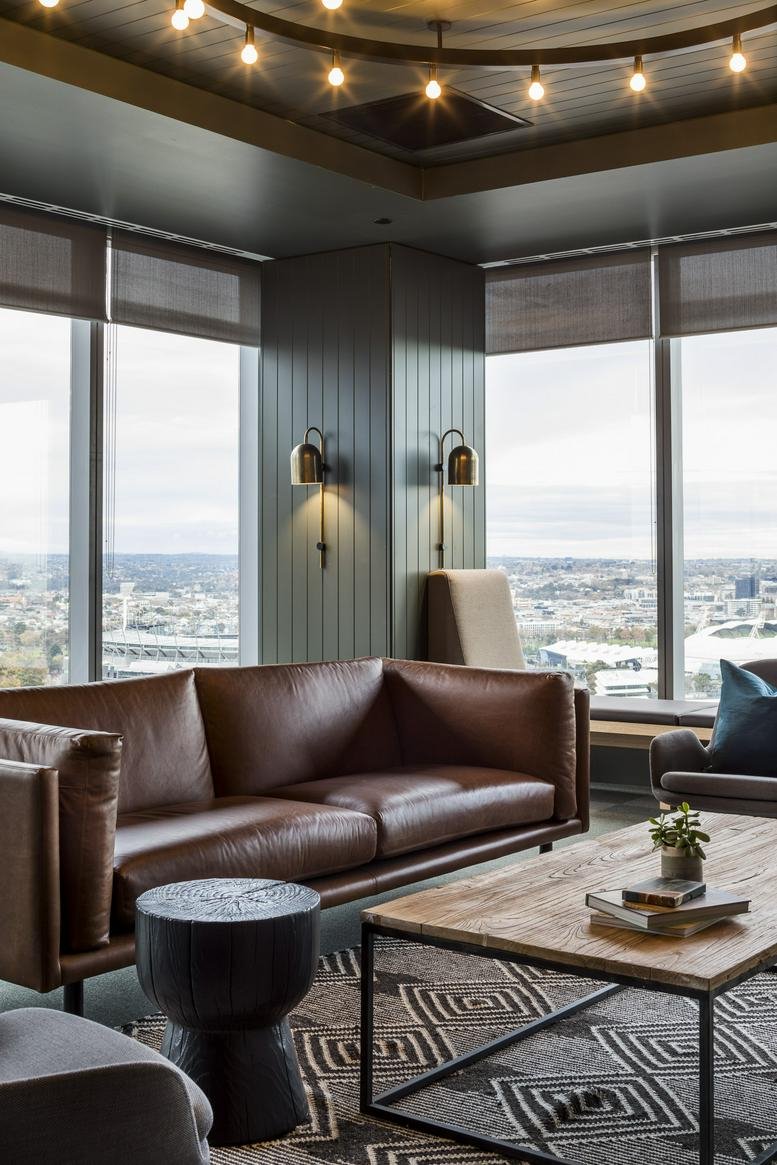 Modern lounge area at Level 12, 360 Elizabeth Street featuring leather sofas and city views.