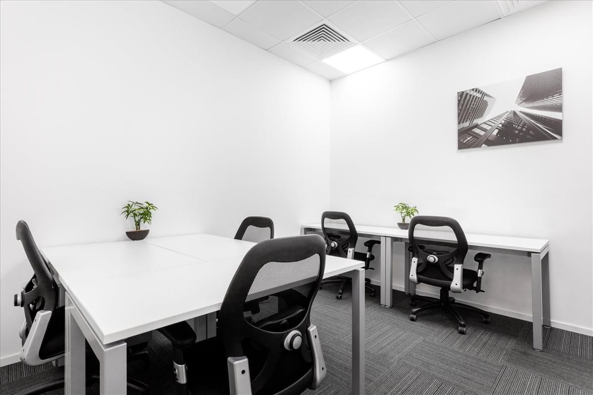 Spacious private workspace at Ajman Chamber of Commerce building, Corniche with modern desks and black mesh chairs.