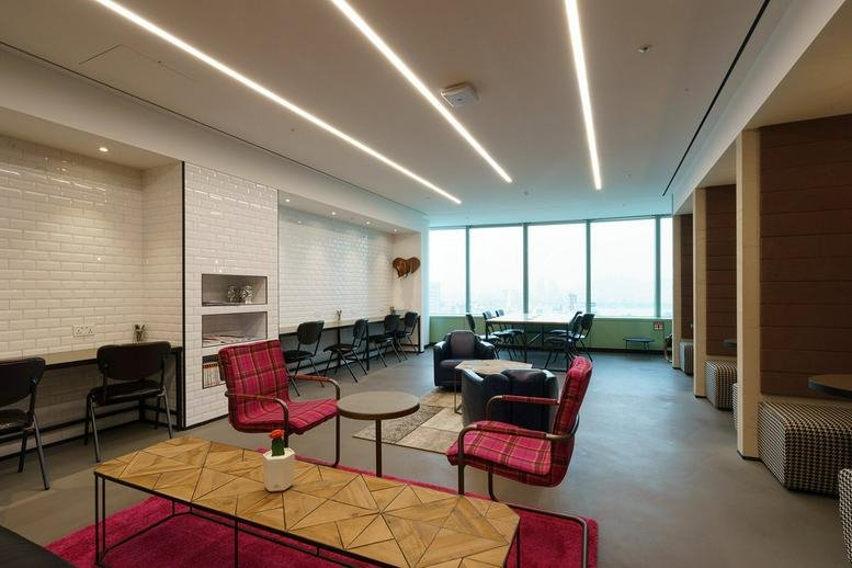 Spacious communal lounge at Level 35, The Gateway West with red armchairs and floor-to-ceiling city views.