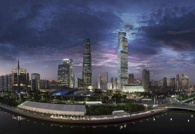 Dusk skyline view showing the illuminated high-rise building alongside the river.