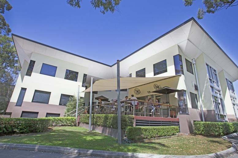 Exterior view of the white multi-story Garden City Office Park building with a shaded outdoor patio.