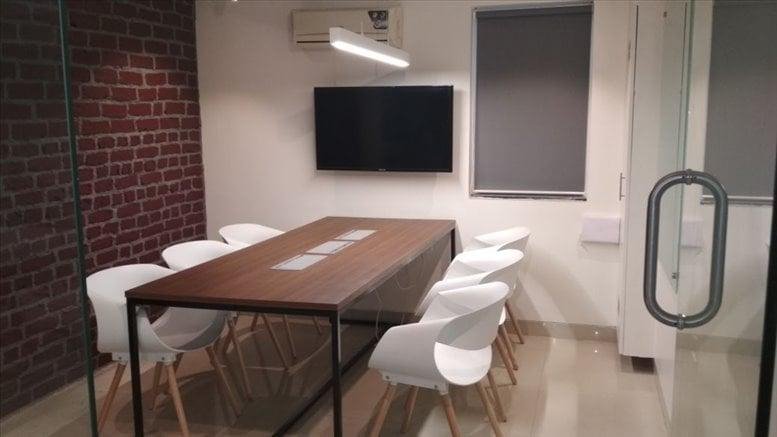 Meeting room at M G Road, Ballard Estate, Fort, Mumbai, Maharashtra with a dark wood table and red brick accent wall.