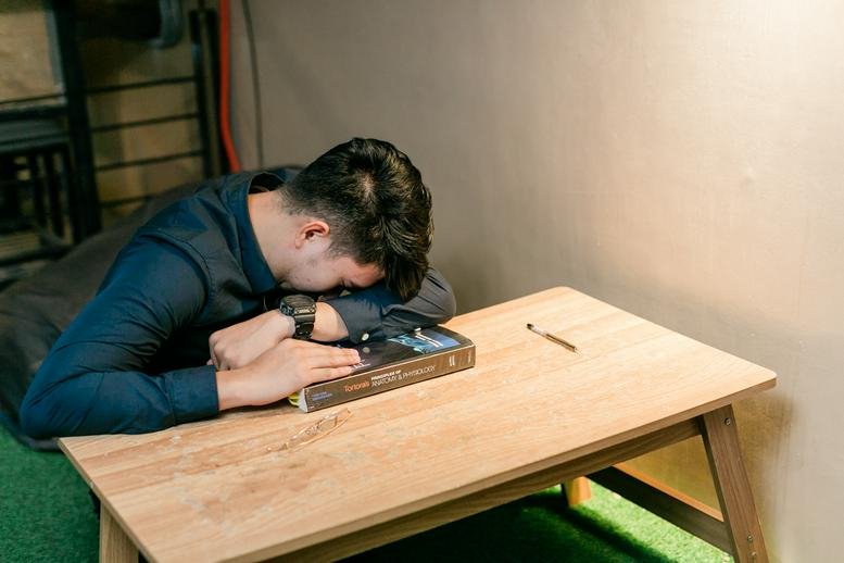 Individual at a desk resting on a book.