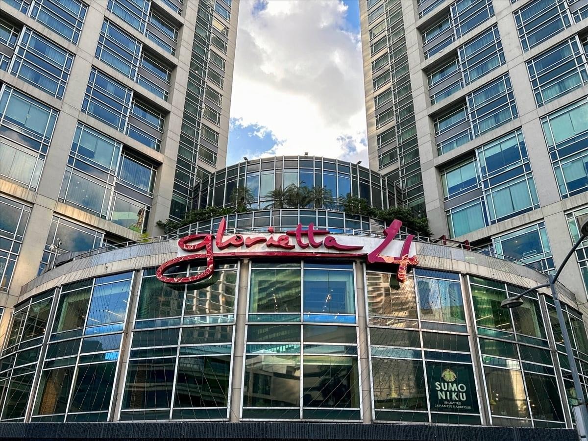 Wide exterior shot of the Glorietta 4 entrance between two glass skyscrapers.