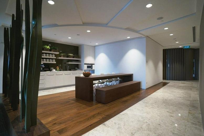 Modern communal kitchen and lounge area with warm wood flooring and marble tiles.