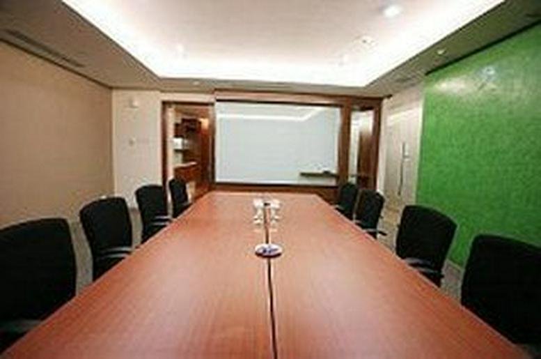 Spacious boardroom with a long wooden table and a vibrant green accent wall.
