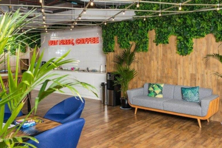 Spacious breakout lounge with wood-paneled walls and a lush green vertical garden at Media One.