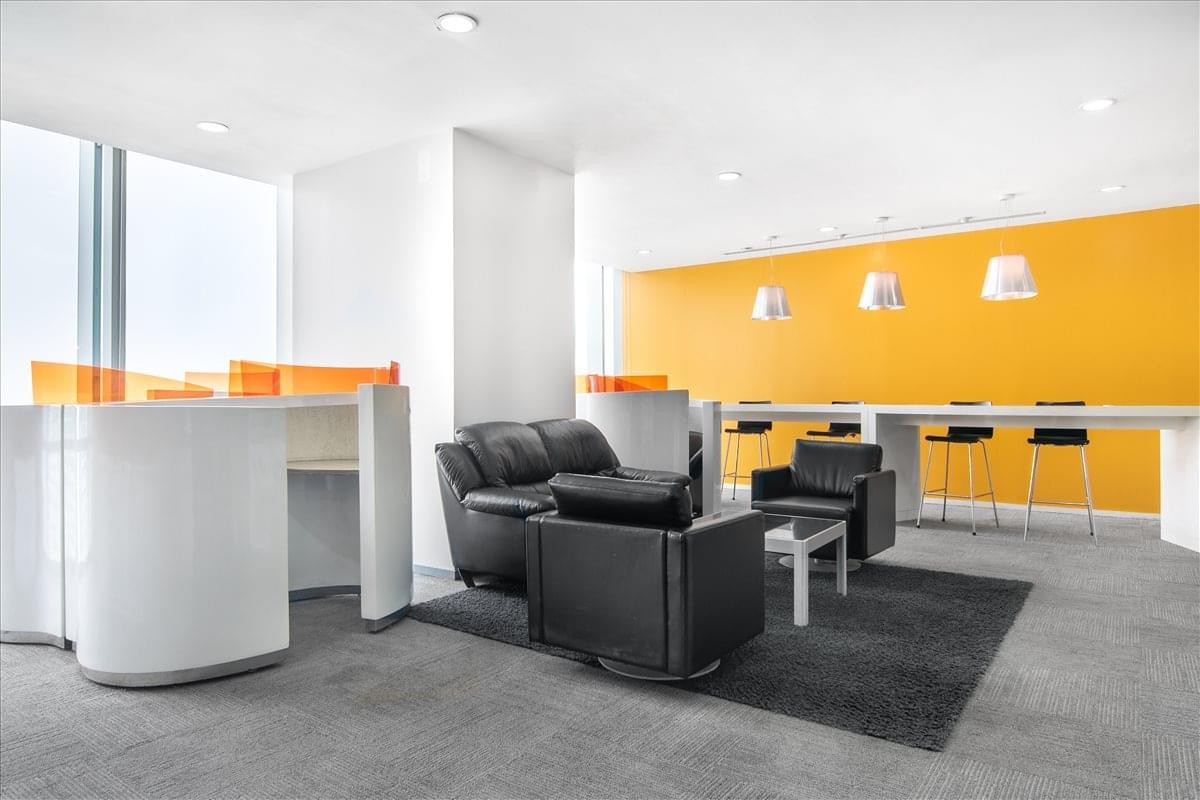 Spacious lounge area with black leather armchairs and a bright yellow accent wall.