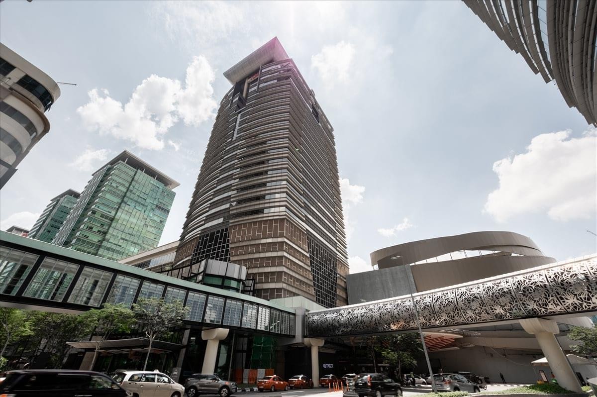 A dramatic low-angle view of the high-rise Menara IGB tower with glass pedestrian walkways.