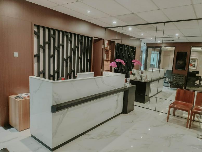 Modern marble reception desk at Menara Rajawali with a decorative screen and purple orchids.