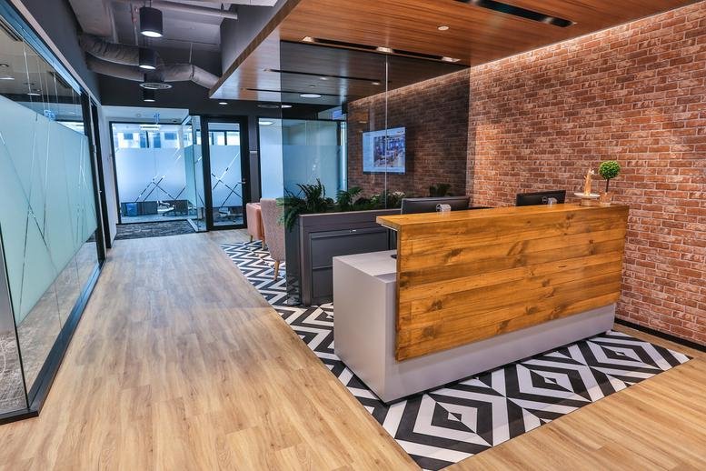 Reception area at Menara Standard Chartered with a wooden desk and a brick feature wall.