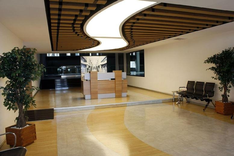 Reception lobby at Merkez Mah, Abide-i Hürriyet Caddesi with curved ceiling lights and wooden slat details.