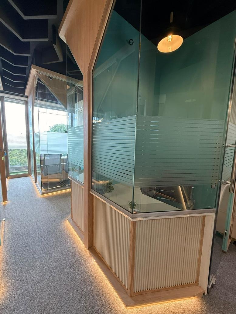 Modern corridor at Absolute CoSpace with glass-walled private office pods and warm under-lighting.