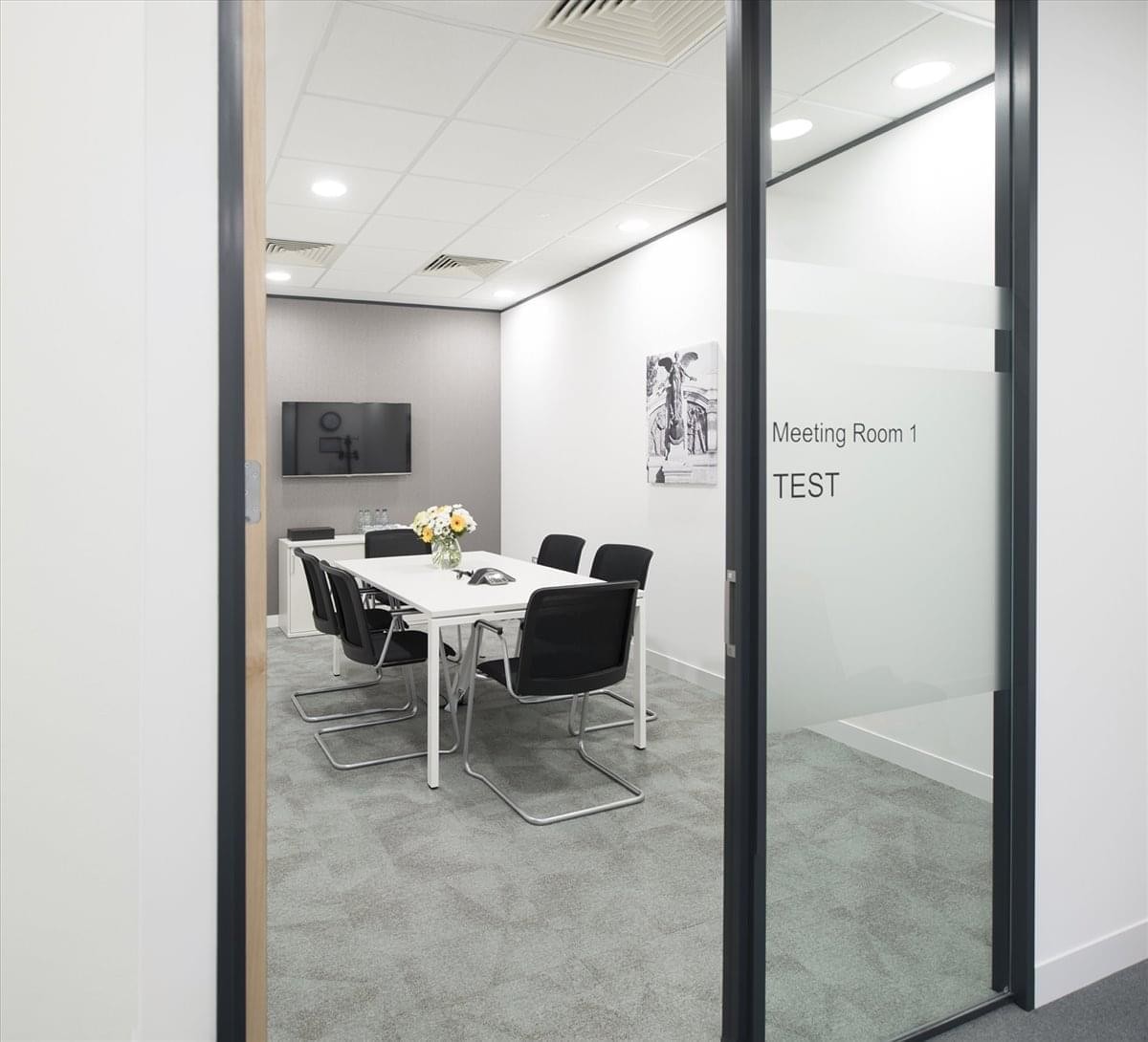 Bright glass-walled meeting room at 4th floor 1-5-11, Nagoya City featuring a white table and black chairs.
