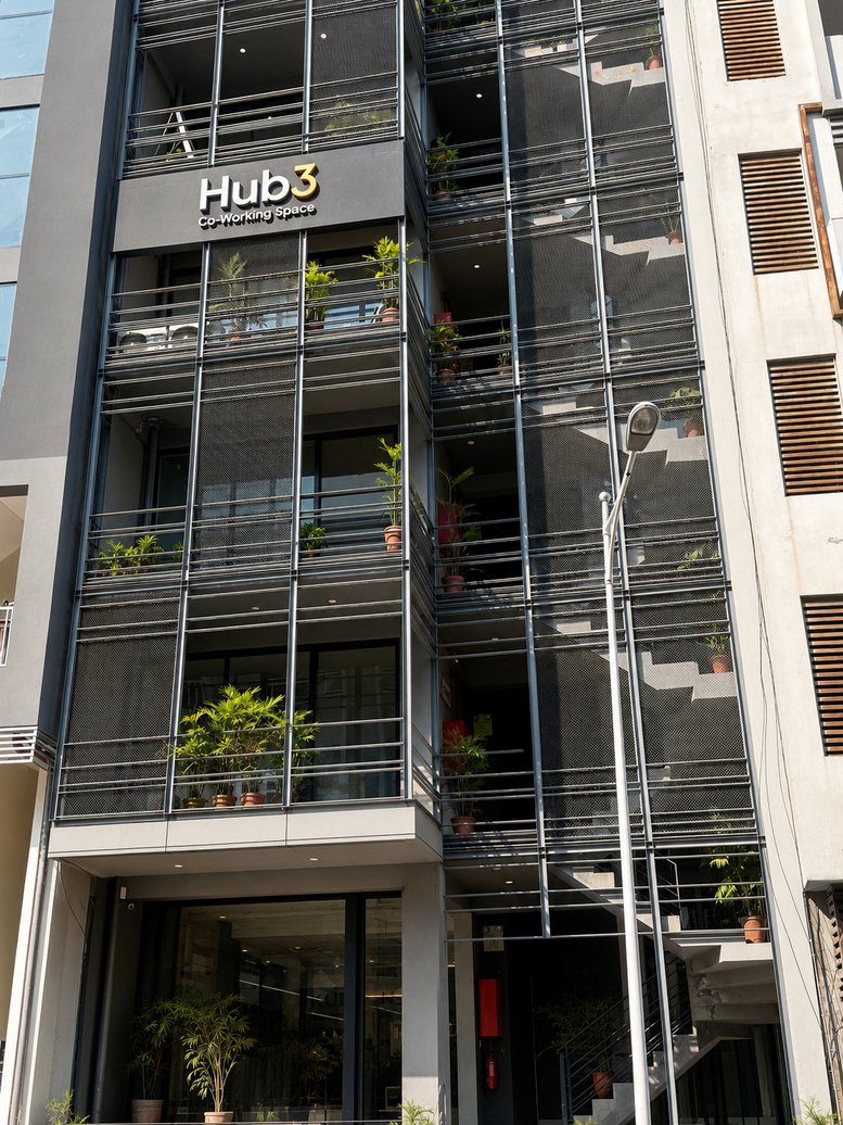 Exterior view of the modern multi-story Hub3 Co-Working Space building with glass balconies and plants.