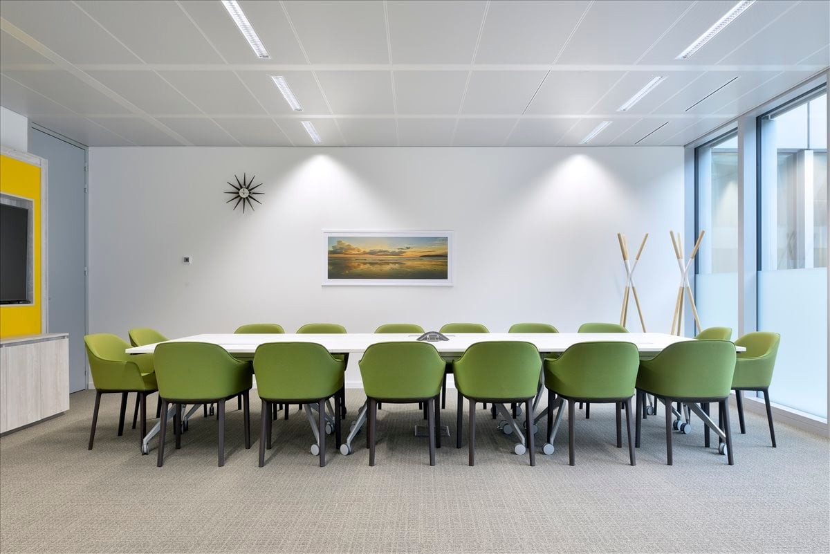 Spacious boardroom at Homeland Kalyan Chakravarty, Gandhi Nagar with green chairs and minimalist wall art.