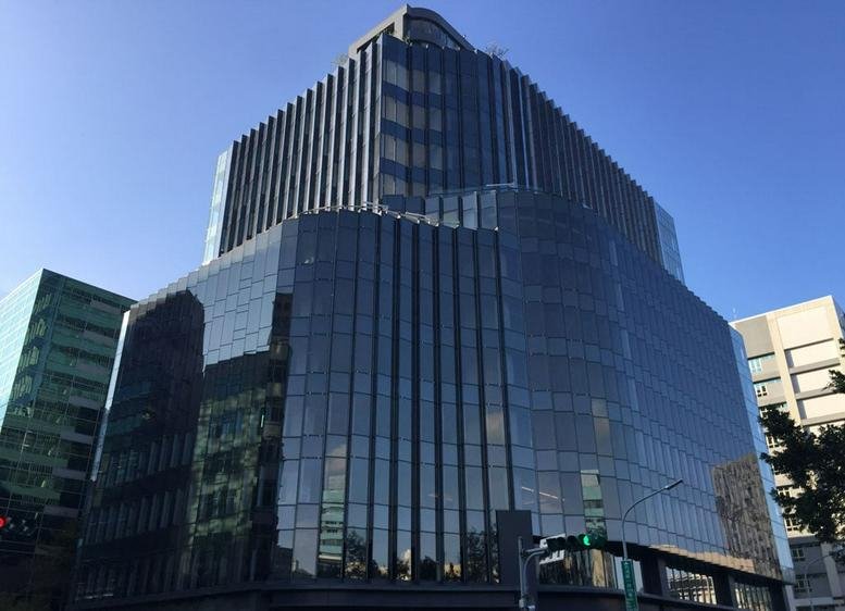 Exterior view of the glass-facade Neihu New Century Building against a clear blue sky.