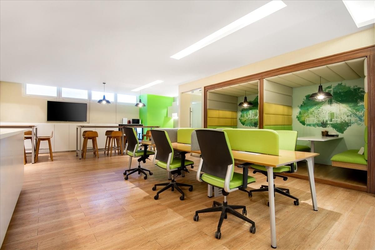 Spacious open-plan workspace at Nimr Al Nakheel centre with green desks and wood-style flooring.