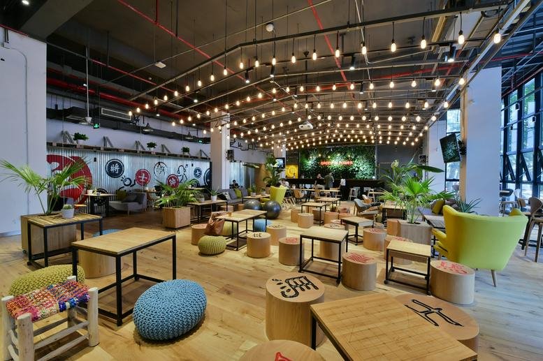 Spacious communal lounge at No. 14 Jiuxianqiao Rd, C& W Industrial Park with warm wood floors and string lighting.