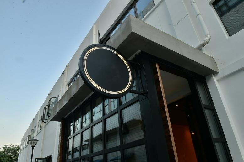 Exterior entrance of the building at No. 14 Jiuxianqiao Rd, C& W Industrial Park with a round black sign and glass doors.