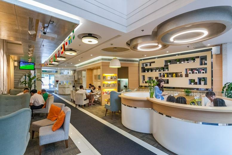 Social hub and reception area with curved white desks and hanging ring lights.