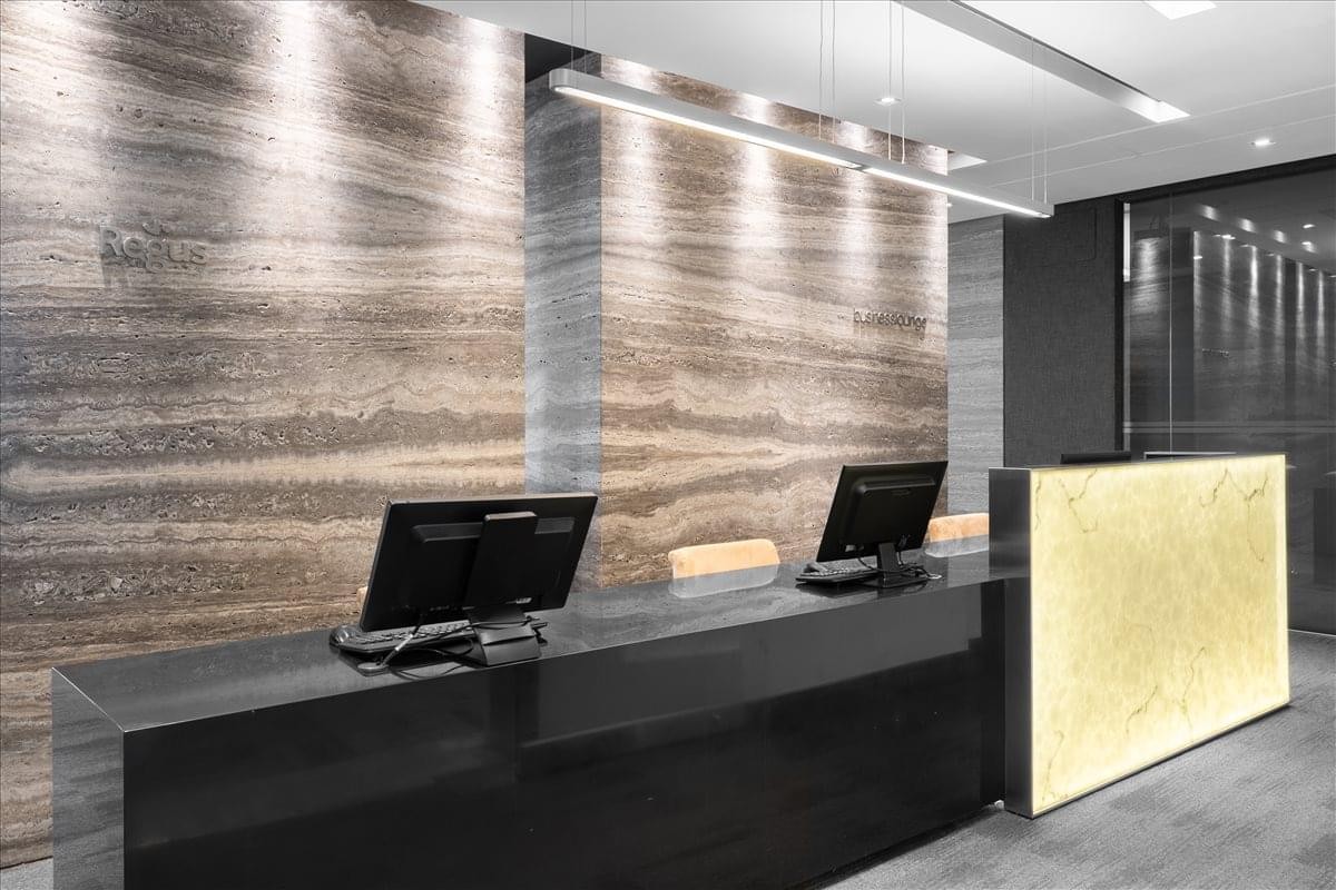Reception area featuring a dark stone desk and backlit feature walls with textured panels.