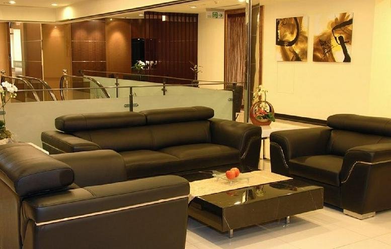 Spacious communal lounge featuring dark leather sofas and a glass coffee table.