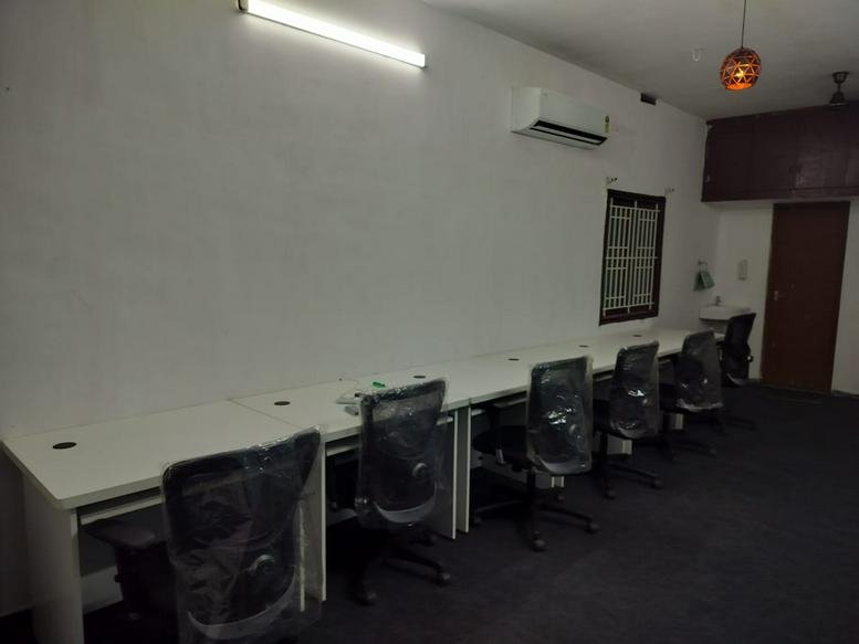 Open-plan office with a long white communal desk and ergonomic mesh chairs at 4B, 3rd Street, Raja Nagar, Ganapathy.