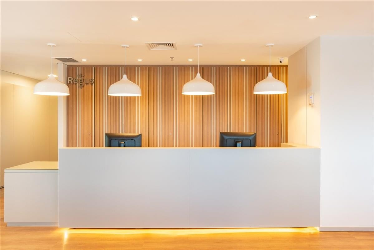 Bright modern reception area with a long white desk and warm wood-paneled feature wall.