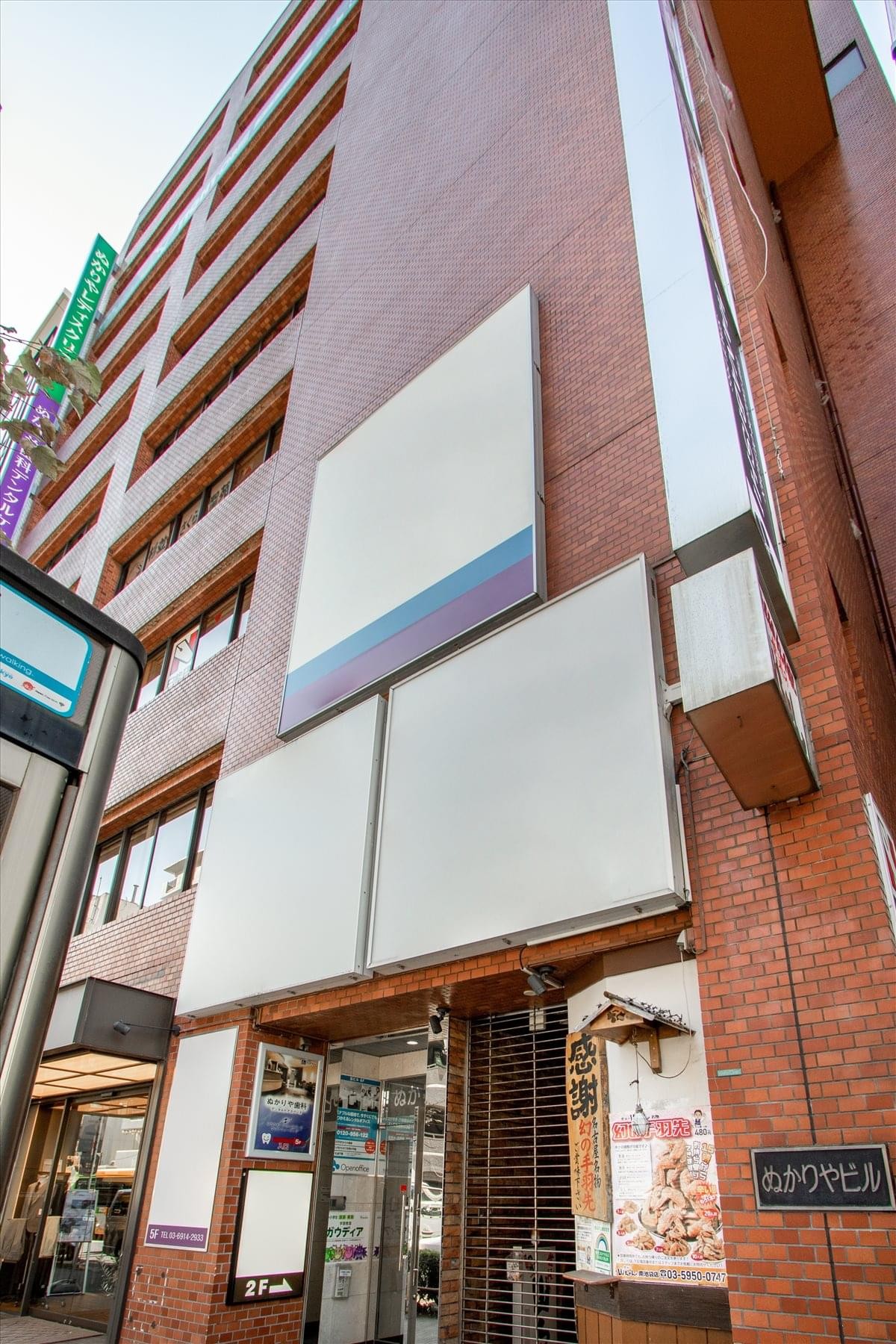 Facade of the red brick Nukariya Building 6F with various business signage.