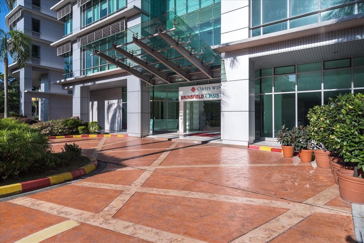 Ground level exterior view of the modern Brunsfield Oasis Tower 3 building with paved entrance.