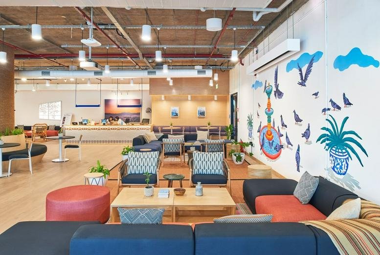 Colorful open lounge at Oberoi Commerz II featuring a mural, potted plants, and plush seating.