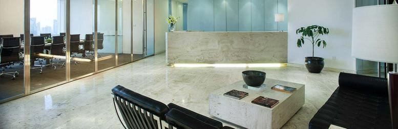 Bright reception lobby with a stone desk, potted plant, and modern seating.