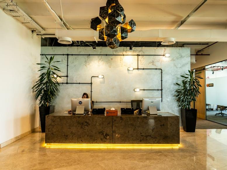 Reception area at OneJLT-05-00 Jumeirah Lake Towers with a stone desk and industrial pipe lighting.