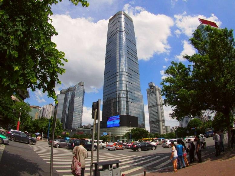 Wide-angle street view of the glass skyscraper Onelink International Center against a blue sky.