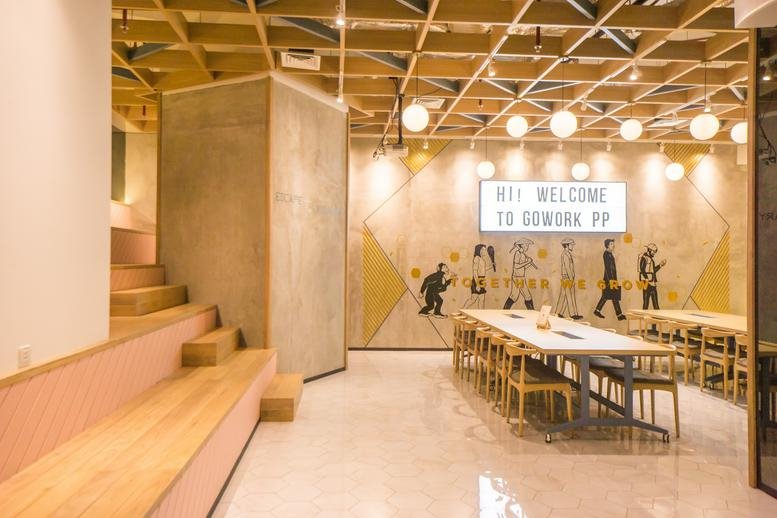 Spacious lounge at Pacific Place Mall featuring tiered wooden seating and a mural with modern lighting.