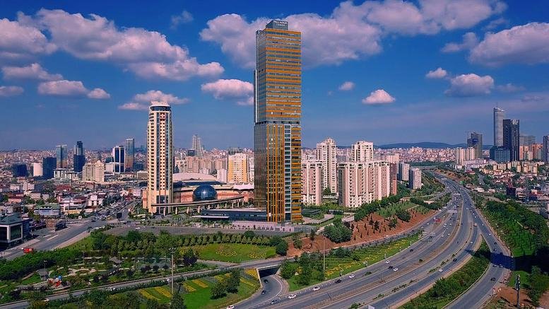 Wide exterior view of the golden-glass facade Palladium Tower amidst the Istanbul skyline.