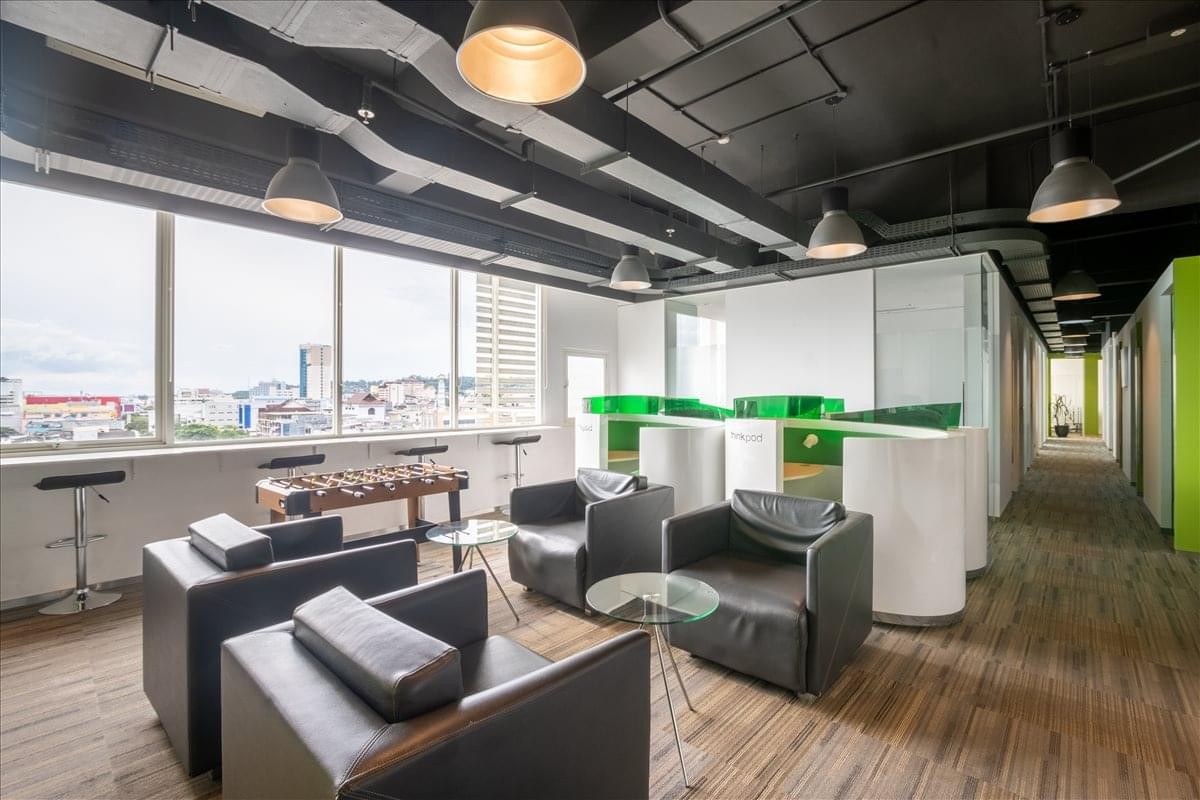 Spacious breakout lounge with leather armchairs, a foosball table, and industrial-style ceilings.