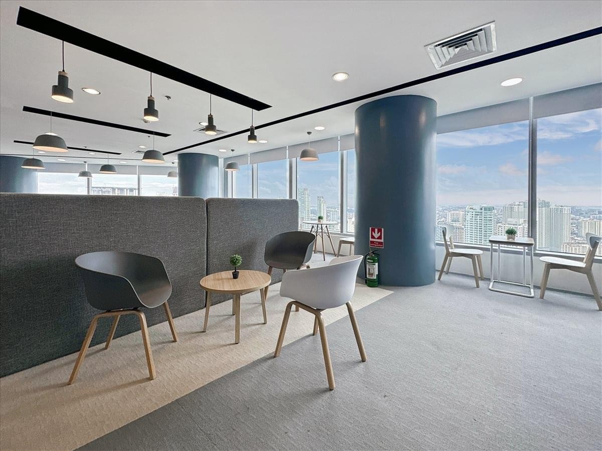 Sunlit communal lounge with grey booth seating and panoramic city views.