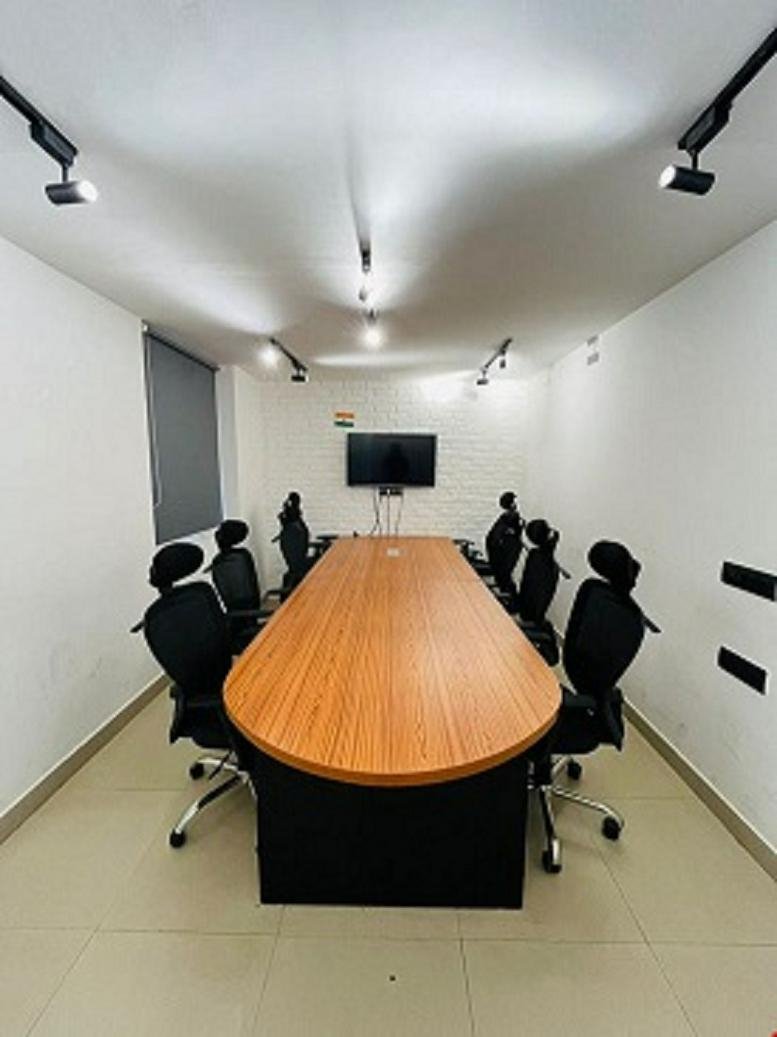 Meeting room at Plot 14, Yudhister Marg, ESIC Colony, C Scheme, Jaipur with a long wood-toned table and black chairs.