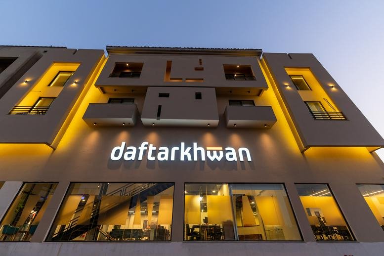 Exterior view of the modern Daftarkhwan | Vantage building with illuminated signage at dusk.